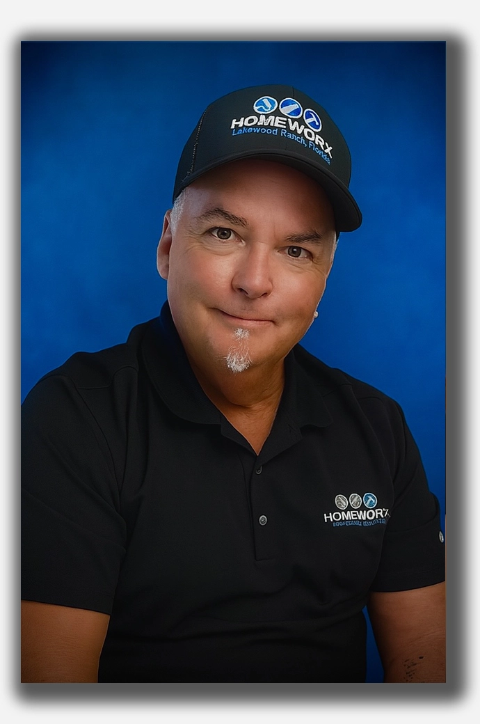 Head-and-shoulders portrait of Bob Leider, co-founder of Homeworx, wearing a black Homeworx polo and cap, smiling against a solid blue backdrop.