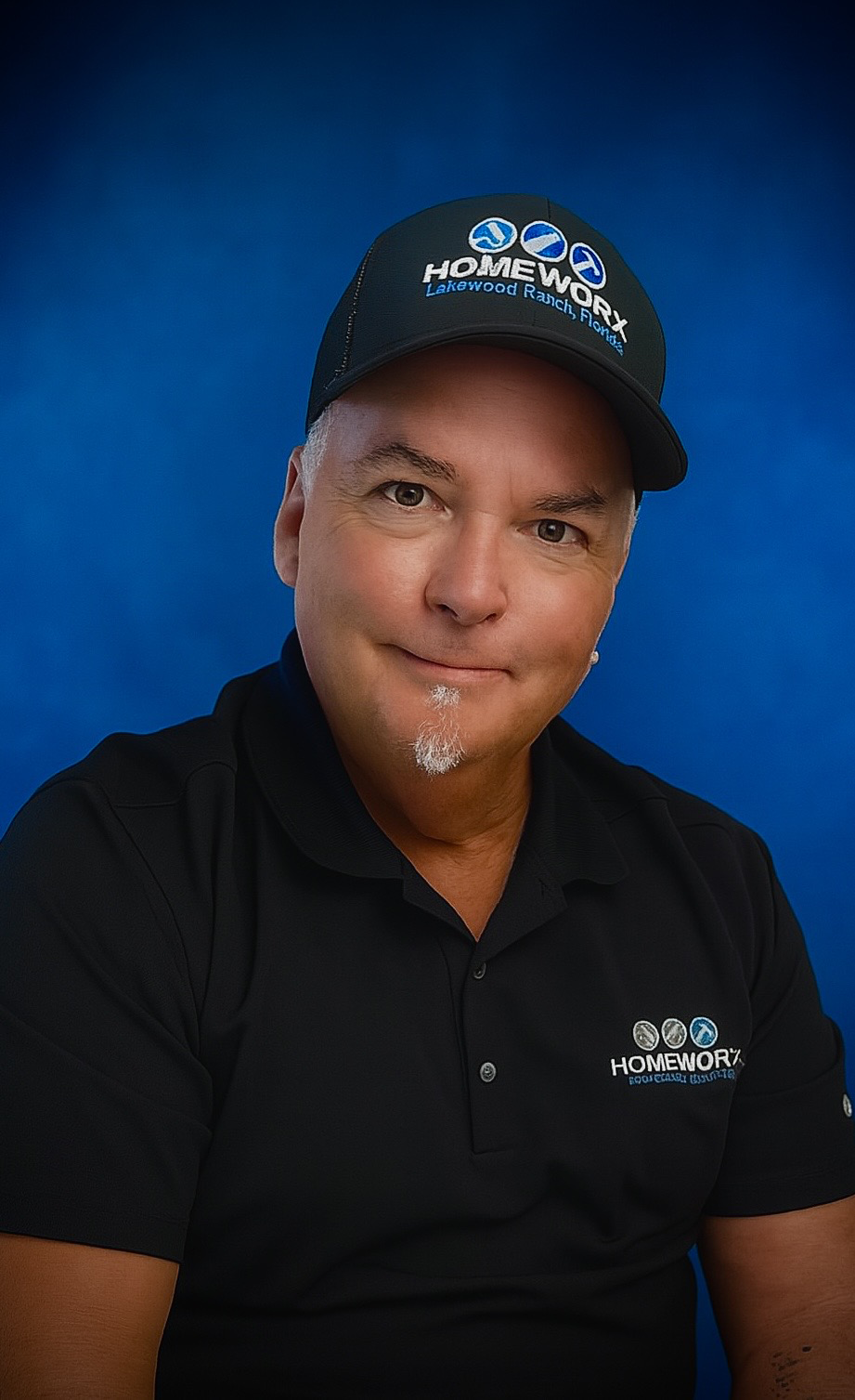 Head-and-shoulders portrait of Bob Leider, co-founder of Homeworx, wearing a black Homeworx polo and cap, smiling against a solid blue backdrop.