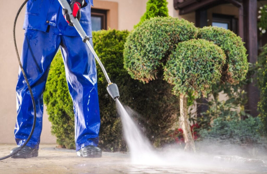 Closeup of a man pressure washing a driveway.