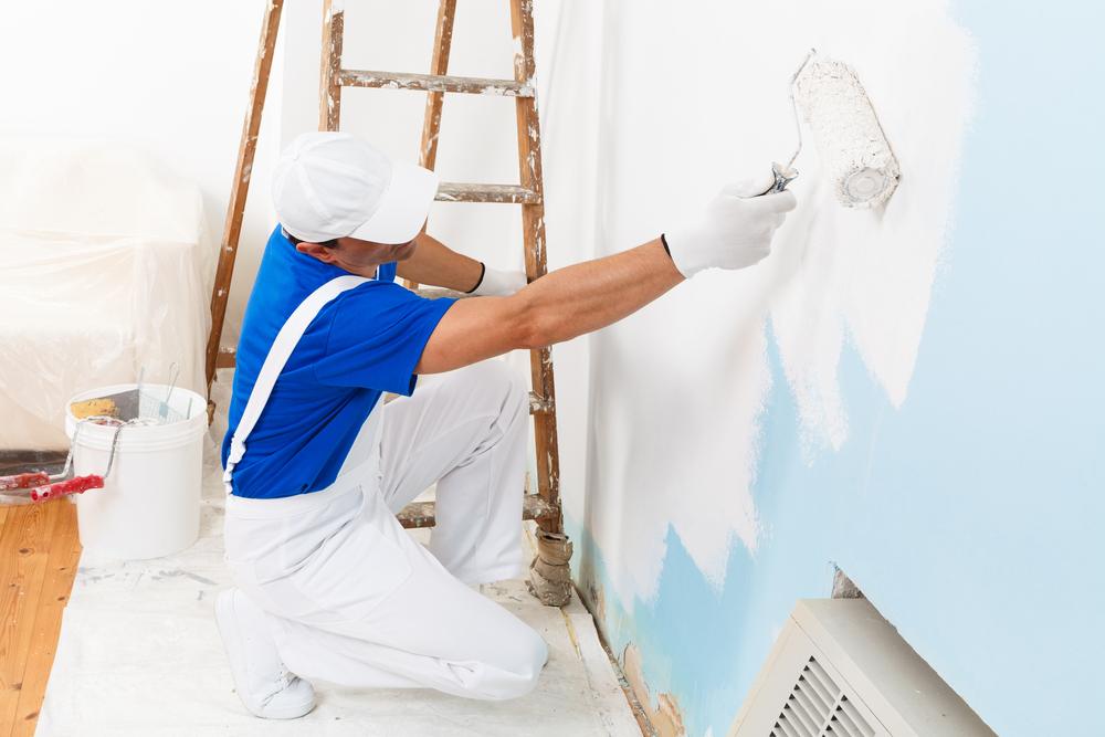 Man painting an interior room wall.